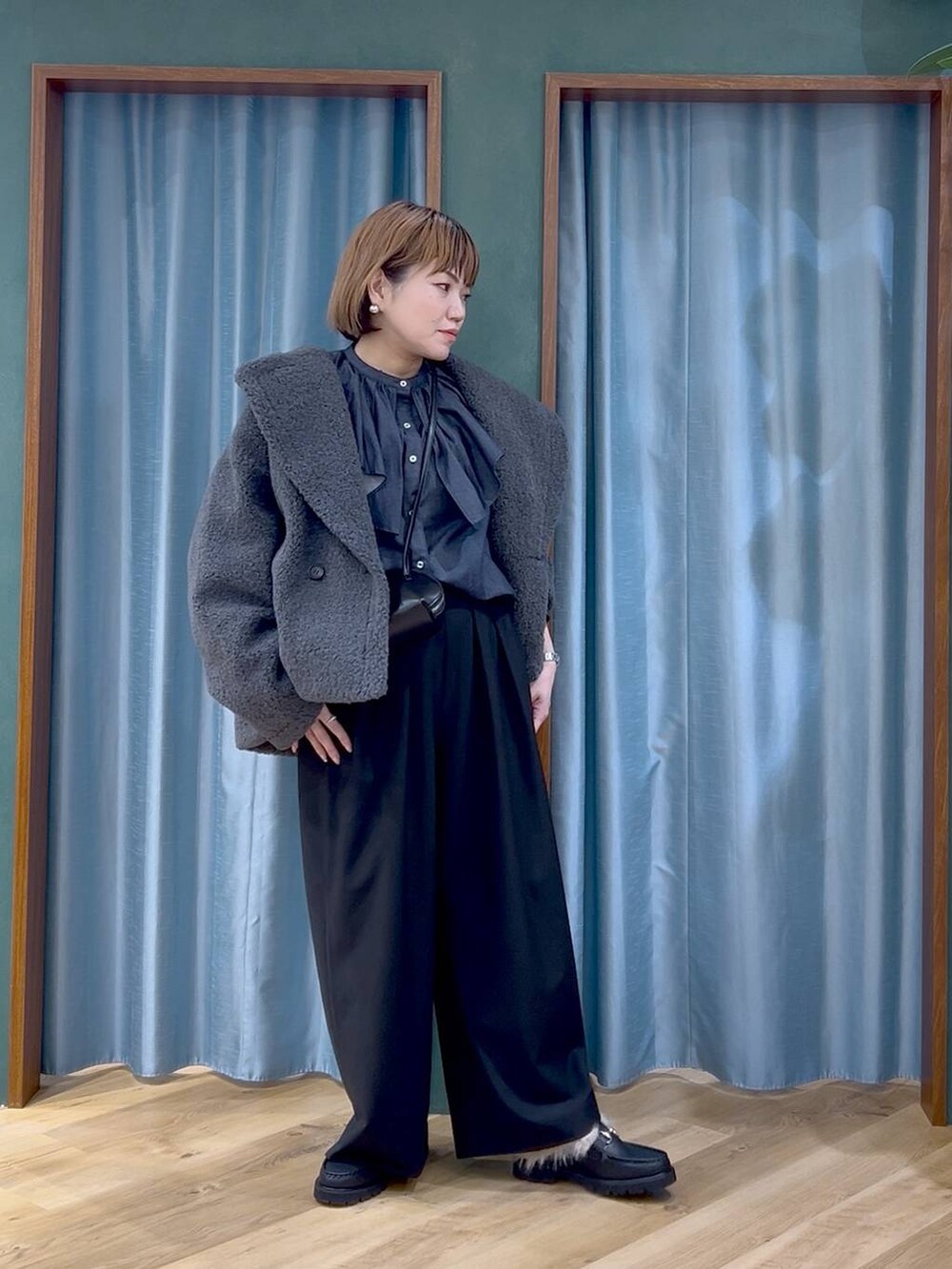 グレー系のピーコート、ブラック系のショルダーバッグ、ブラック系のスラックスを着用したレディースの秋コーディネートの2枚目の写真