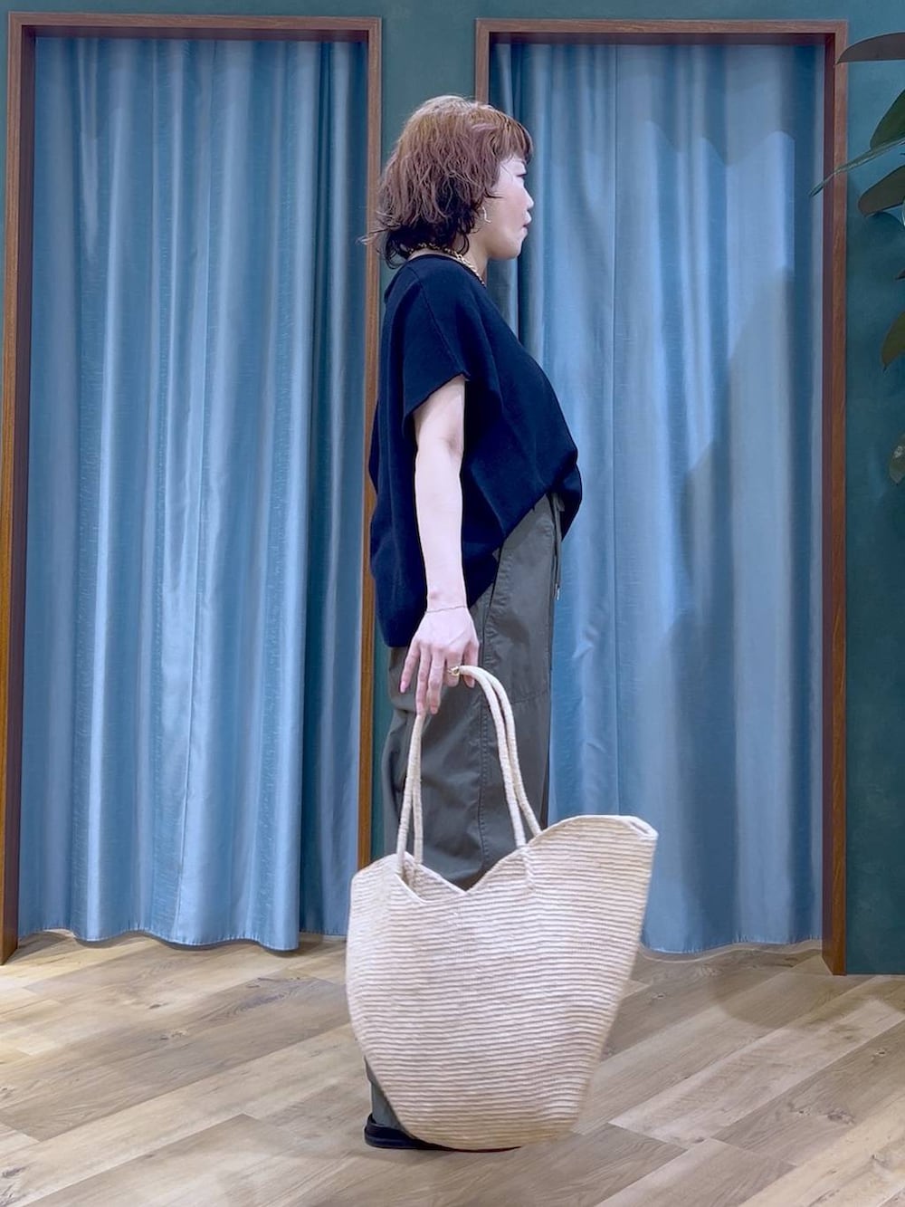 グリーン系のカーゴパンツ、ブラック系のサンダル、ベージュ系のかごバッグを着用したレディースの夏コーディネートの6枚目の写真