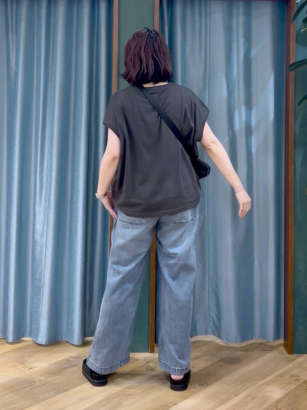 ブラック系のTシャツ/カットソー、ブルー系のデニムパンツ、ブラック系のショルダーバッグを着用したレディースの春コーディネートの5枚目の写真