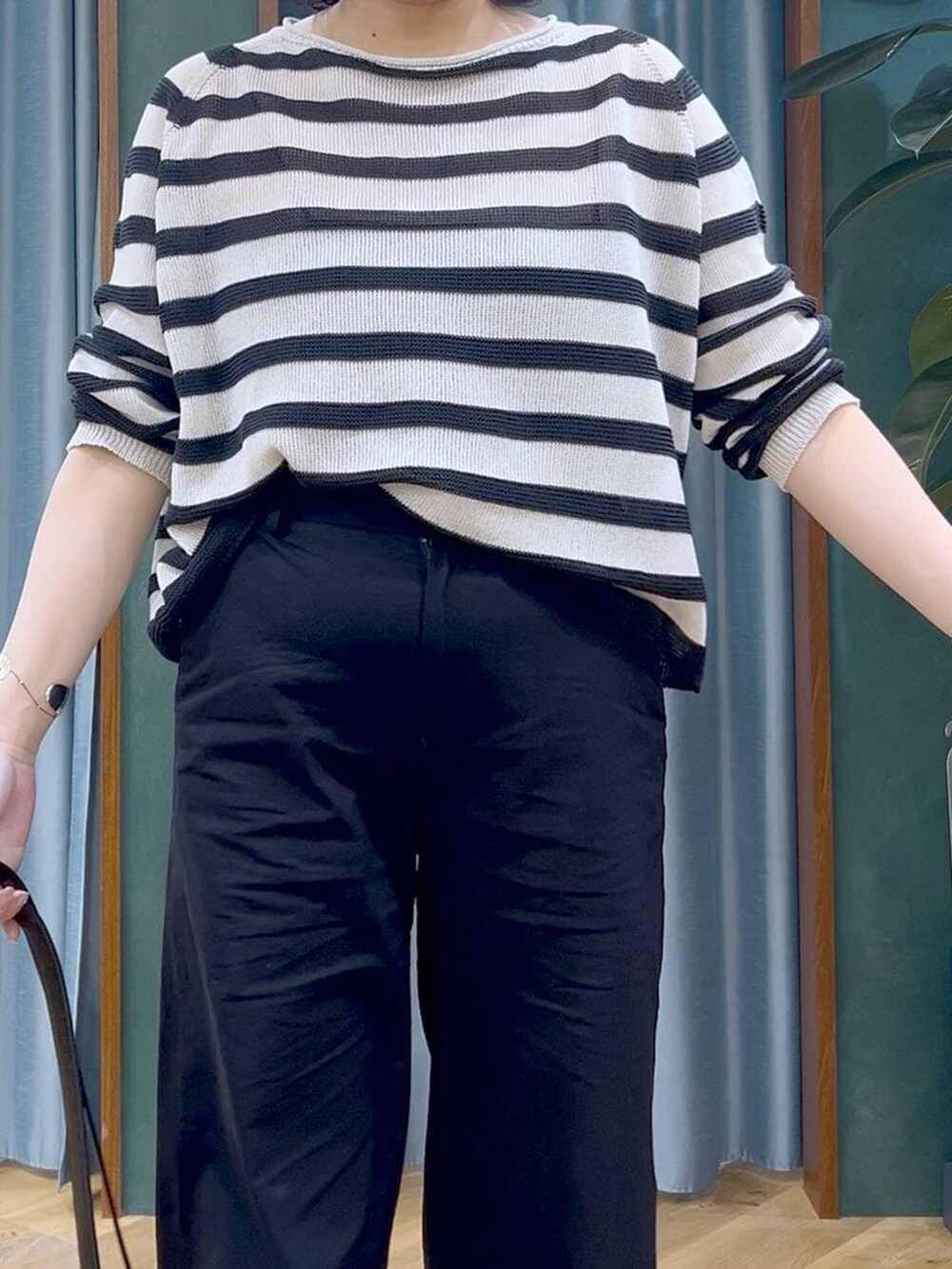 ベージュ系のニット/セーター、ブラック系のその他パンツ、ブラック系のショルダーバッグを着用したレディースの春コーディネートの6枚目の写真