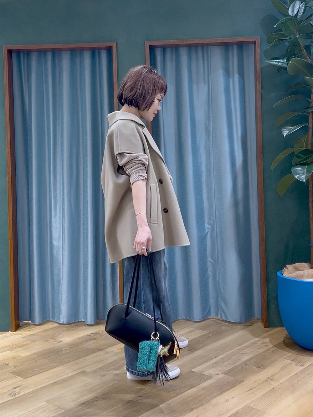 ブラック系のトートバッグ、ブルー系のデニムパンツ、ベージュ系のニット/セーターを着用したレディースの秋コーディネートの3枚目の写真