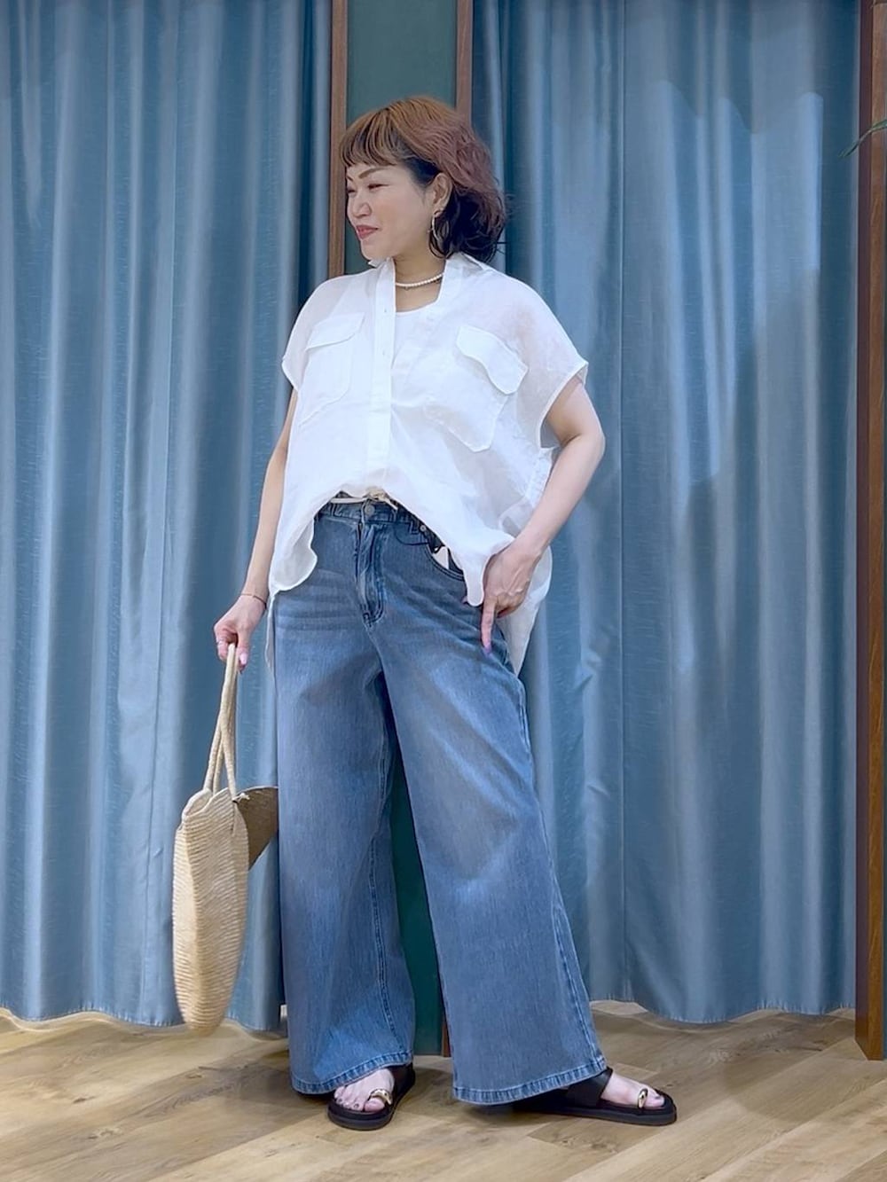ブルー系のデニムパンツ、ホワイト系のタンクトップ、ブラック系のサンダルを着用したレディースの夏コーディネートの4枚目の写真
