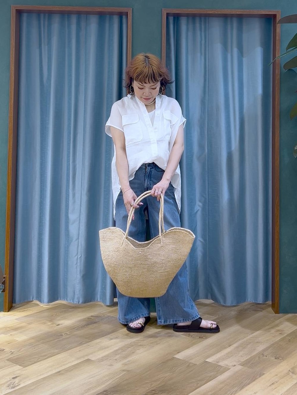ブルー系のデニムパンツ、ホワイト系のタンクトップ、ブラック系のサンダルを着用したレディースの夏コーディネートの3枚目の写真