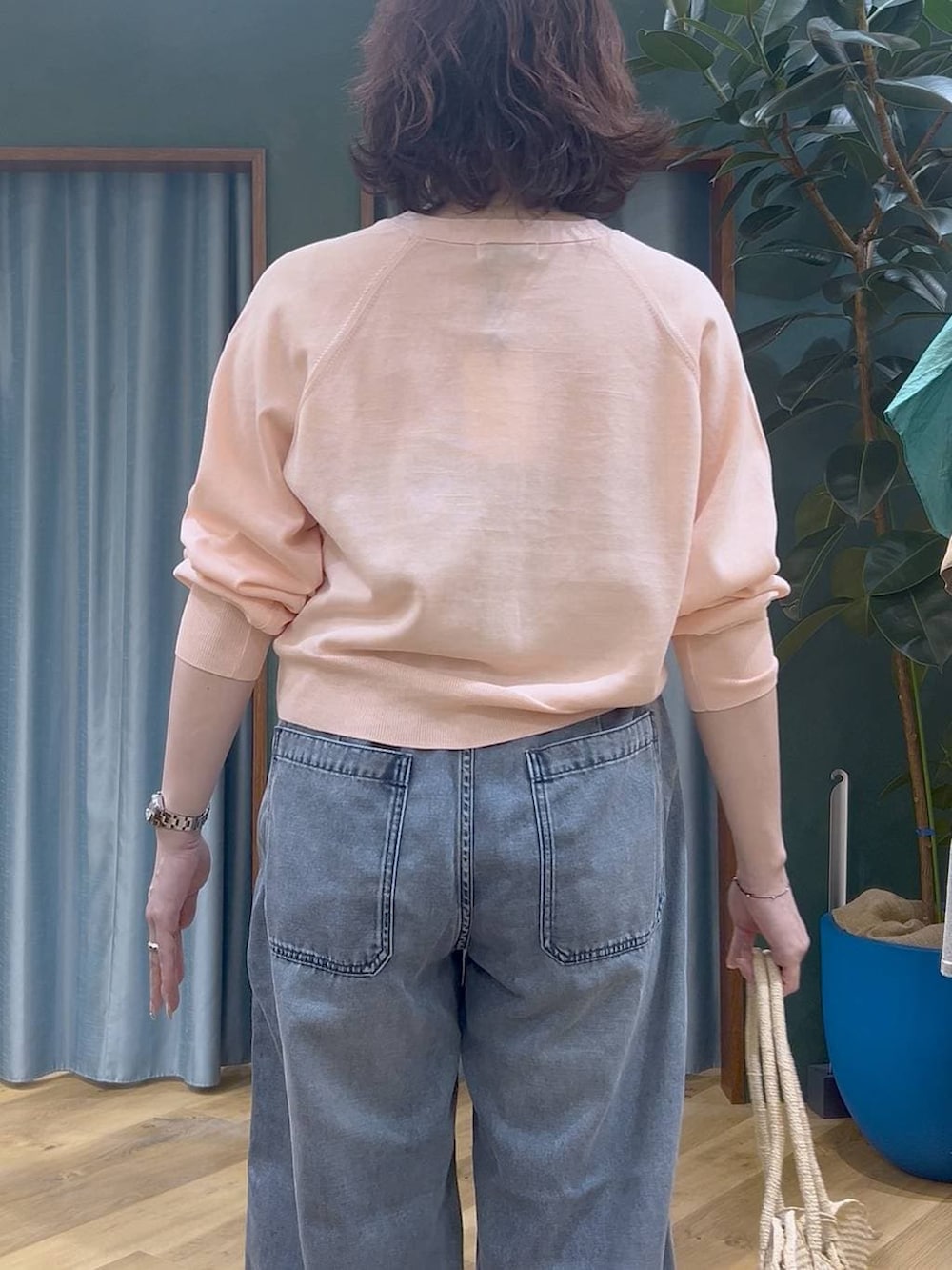ブルー系のデニムパンツ、ピンク系のカーディガン/ボレロ、ベージュ系のかごバッグを着用したレディースの春コーディネートの6枚目の写真
