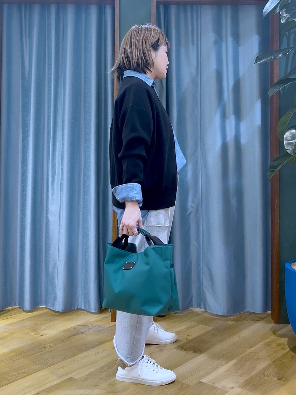 グリーン系のトートバッグ、ブラック系のカーディガン/ボレロ、グレー系のスカートを着用したレディースの冬コーディネートの4枚目の写真