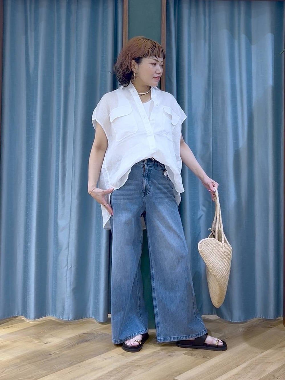 ブルー系のデニムパンツ、ホワイト系のタンクトップ、ブラック系のサンダルを着用したレディースの夏コーディネートの2枚目の写真