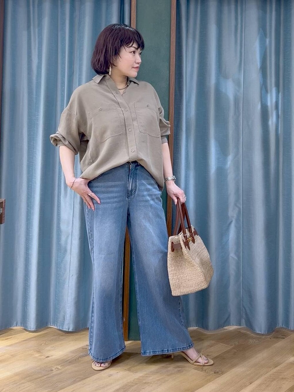 ブルー系のデニムパンツ、グリーン系のシャツ/ブラウス、ベージュ系のかごバッグを着用したレディースの春コーディネートの2枚目の写真