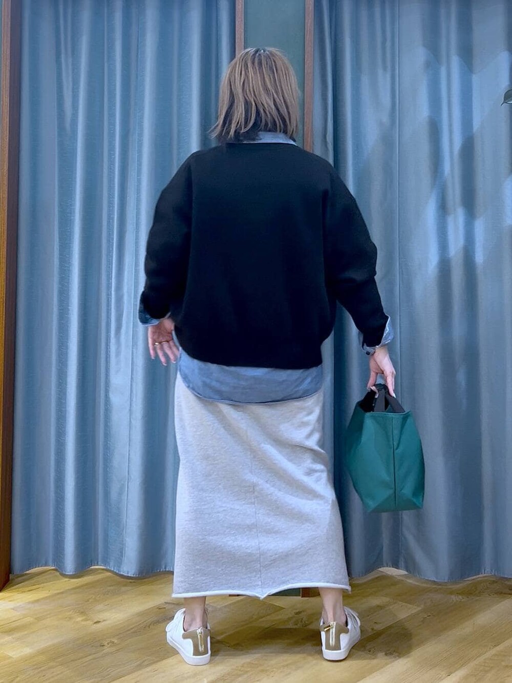 グリーン系のトートバッグ、ブラック系のカーディガン/ボレロ、グレー系のスカートを着用したレディースの冬コーディネートの6枚目の写真