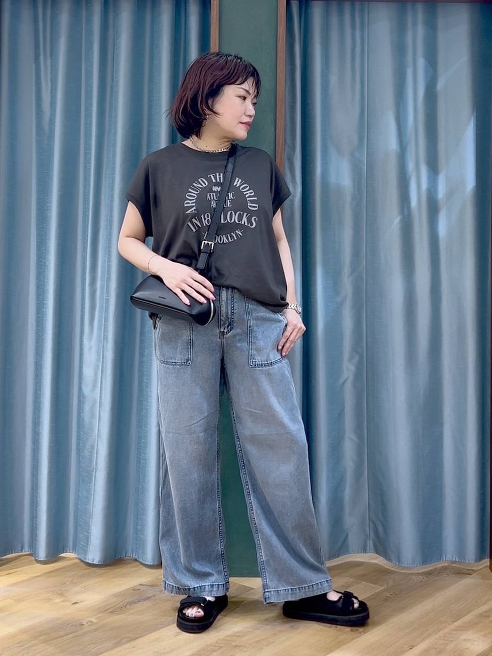 ブラック系のTシャツ/カットソー、ブルー系のデニムパンツ、ブラック系のショルダーバッグを着用したレディースの春コーディネートの2枚目の写真