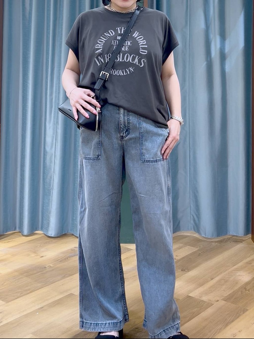 ブラック系のTシャツ/カットソー、ブルー系のデニムパンツ、ブラック系のショルダーバッグを着用したレディースの春コーディネートの6枚目の写真