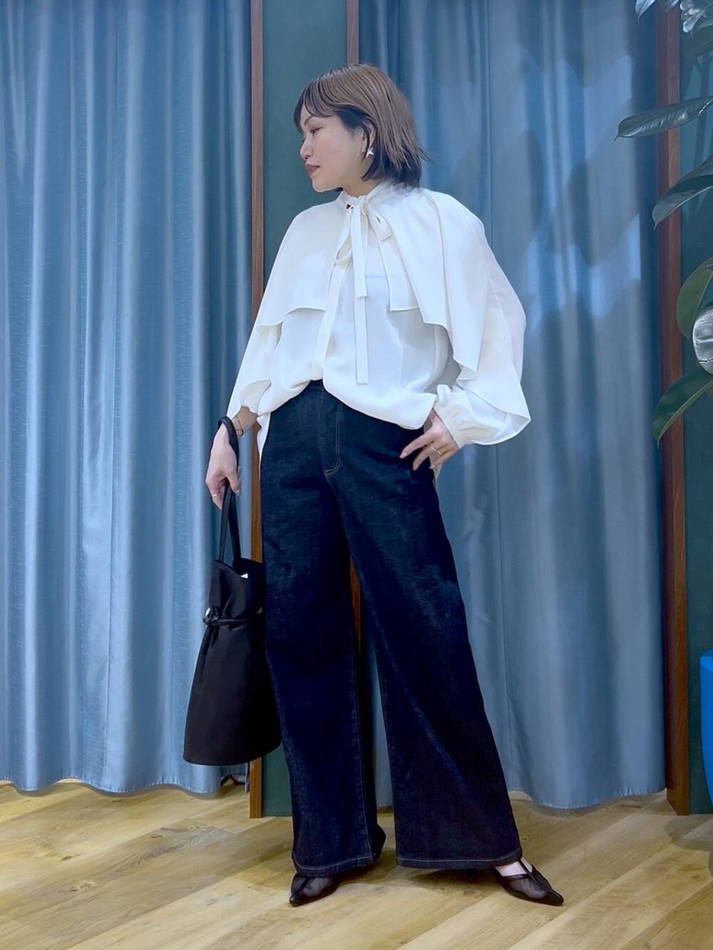 ブルー系のデニムパンツ、ホワイト系のシャツ/ブラウス、ブラック系のトートバッグを着用したレディースの冬コーディネートの2枚目の写真