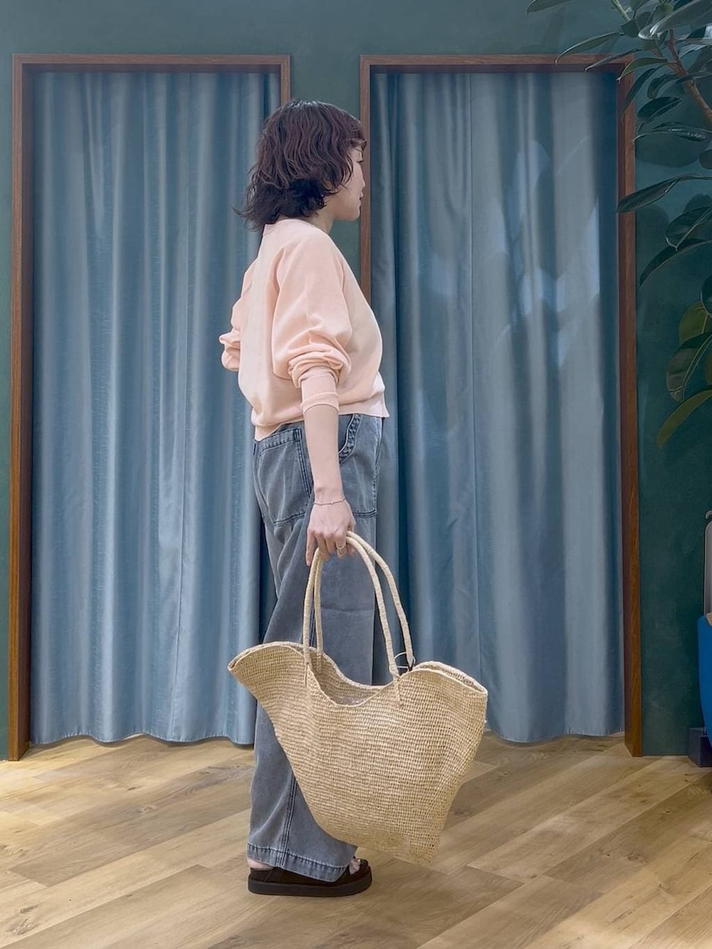 ブルー系のデニムパンツ、ピンク系のカーディガン/ボレロ、ベージュ系のかごバッグを着用したレディースの春コーディネートの3枚目の写真