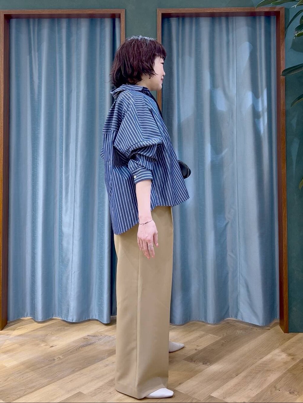 ブルー系のシャツ/ブラウス、ブラック系のショルダーバッグ、ホワイト系のパンプスを着用したレディースの春コーディネートの3枚目の写真