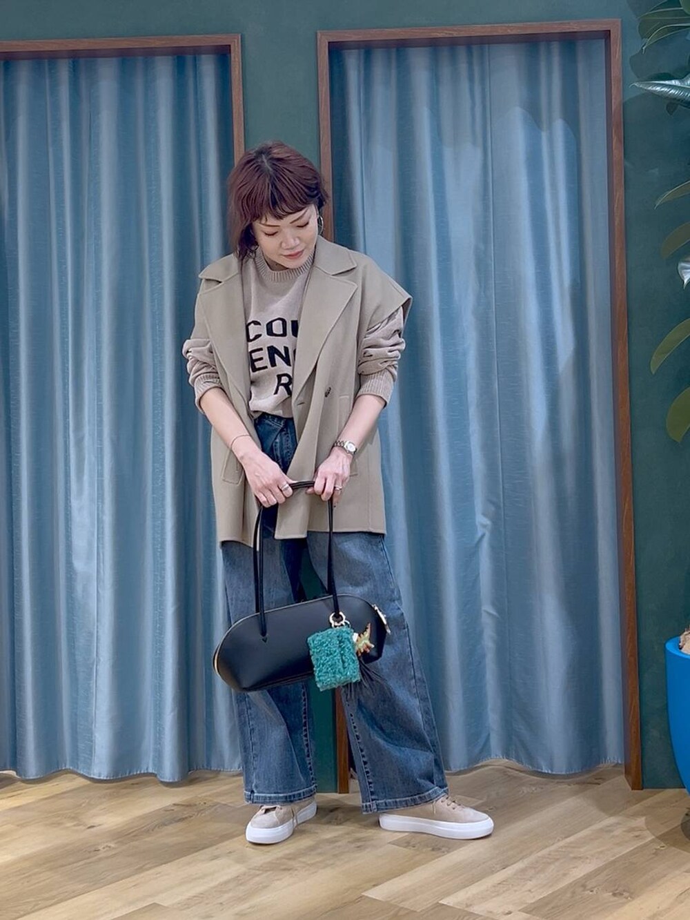 ブラック系のトートバッグ、ブルー系のデニムパンツ、ベージュ系のニット/セーターを着用したレディースの秋コーディネートの2枚目の写真