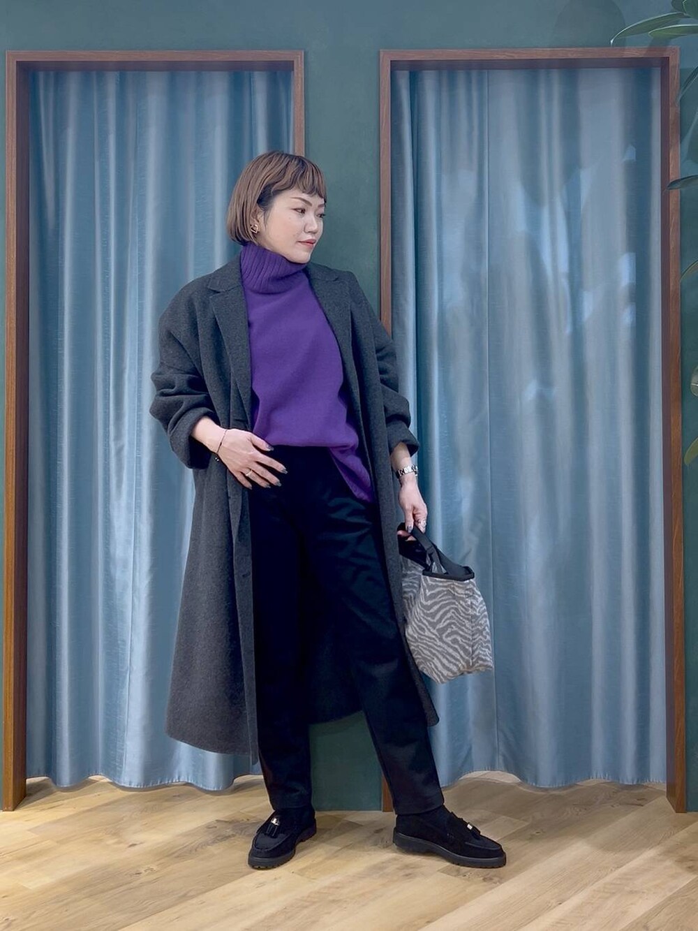 ブラック系のその他パンツ、パープル系のニット/セーター、グレー系のチェスターコートを着用したレディースの秋コーディネートの2枚目の写真