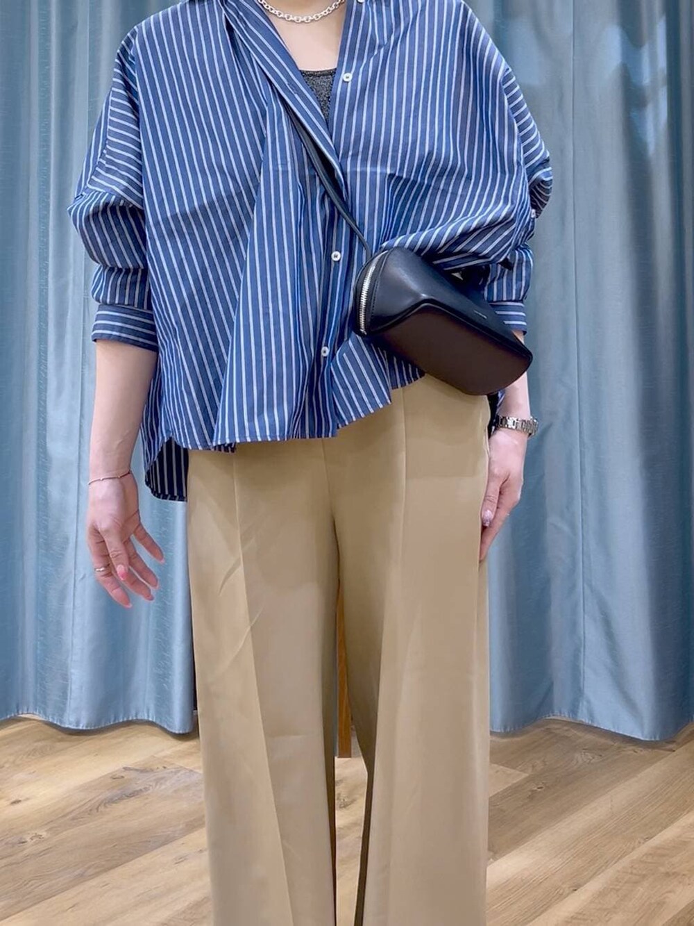 ブルー系のシャツ/ブラウス、ブラック系のショルダーバッグ、ホワイト系のパンプスを着用したレディースの春コーディネートの5枚目の写真