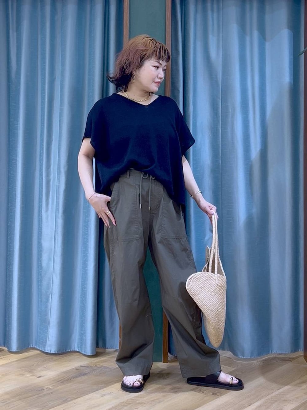 グリーン系のカーゴパンツ、ブラック系のサンダル、ベージュ系のかごバッグを着用したレディースの夏コーディネートの3枚目の写真