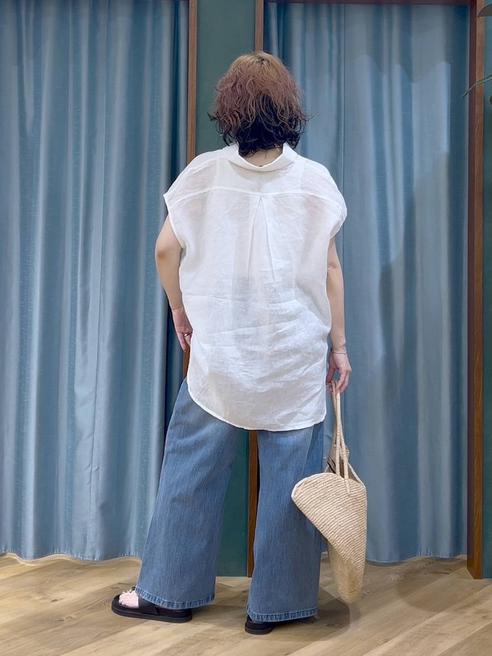 ブルー系のデニムパンツ、ホワイト系のタンクトップ、ブラック系のサンダルを着用したレディースの夏コーディネートの6枚目の写真