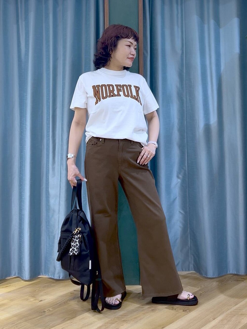 ブラック系のサンダル、ブラック系のバックパック/リュック、ホワイト系のTシャツ/カットソーを着用したレディースの夏コーディネートの2枚目の写真