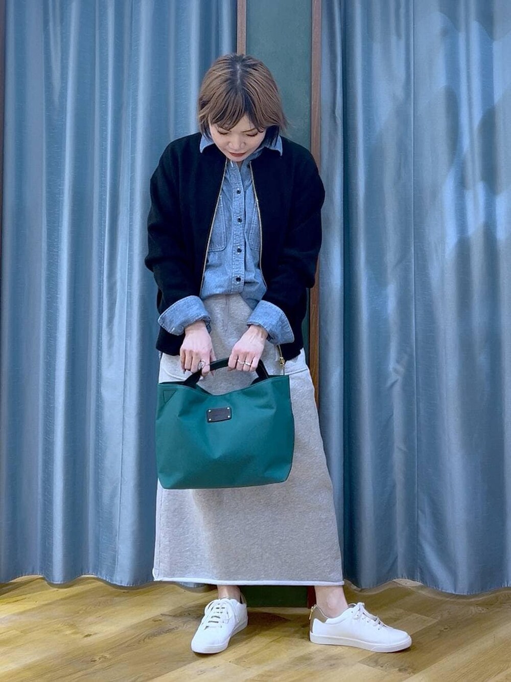 グリーン系のトートバッグ、ブラック系のカーディガン/ボレロ、グレー系のスカートを着用したレディースの冬コーディネートの3枚目の写真