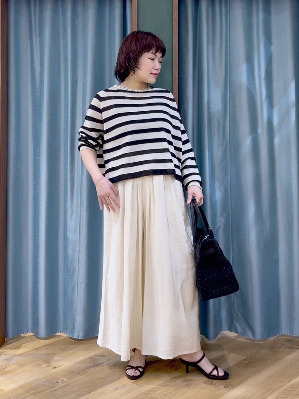 ベージュ系のニット/セーター、ホワイト系のその他パンツ、ブラック系のサンダルを着用したレディースの春コーディネートの2枚目の写真