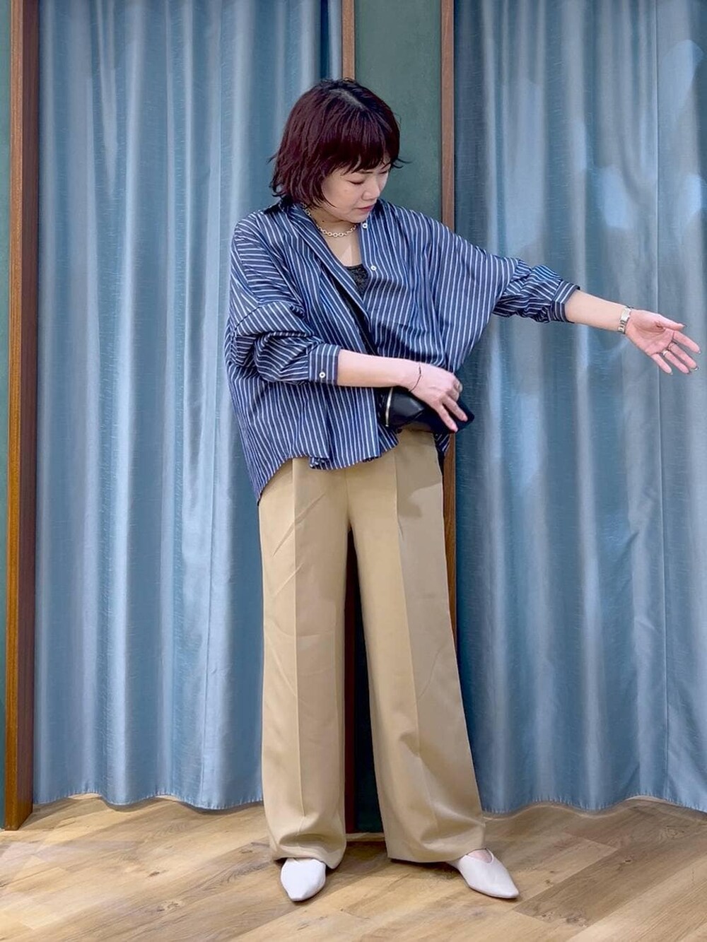 ブルー系のシャツ/ブラウス、ブラック系のショルダーバッグ、ホワイト系のパンプスを着用したレディースの春コーディネートの2枚目の写真