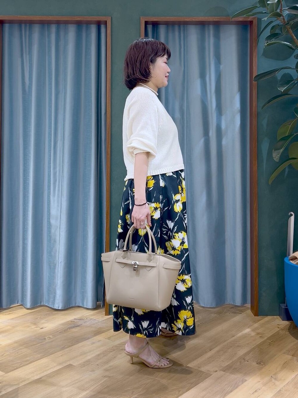 ホワイト系のニット/セーター、ブルー系のスカート、ベージュ系のハンドバッグを着用したレディースの春コーディネートの3枚目の写真