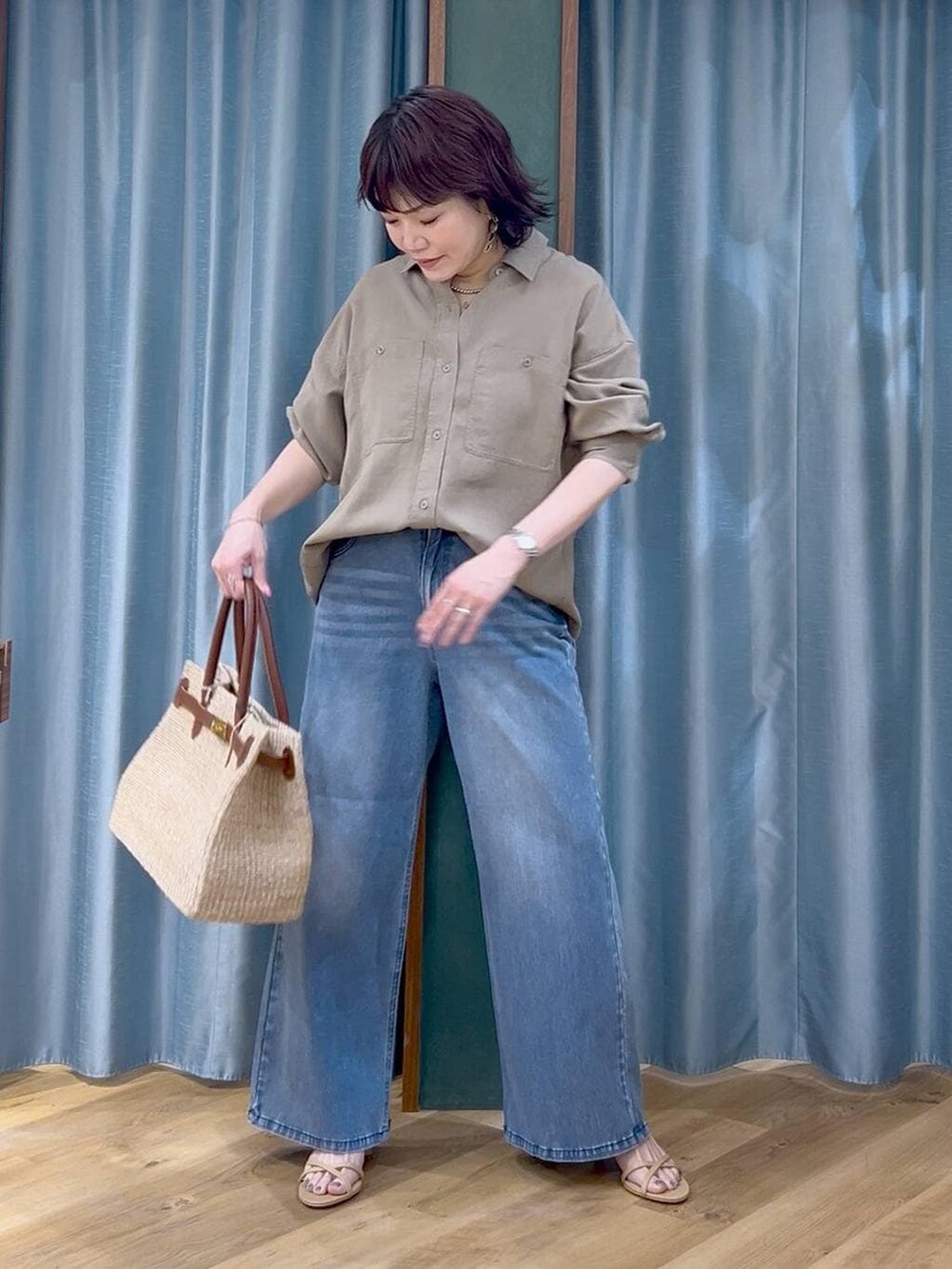 ブルー系のデニムパンツ、グリーン系のシャツ/ブラウス、ベージュ系のかごバッグを着用したレディースの春コーディネートの3枚目の写真