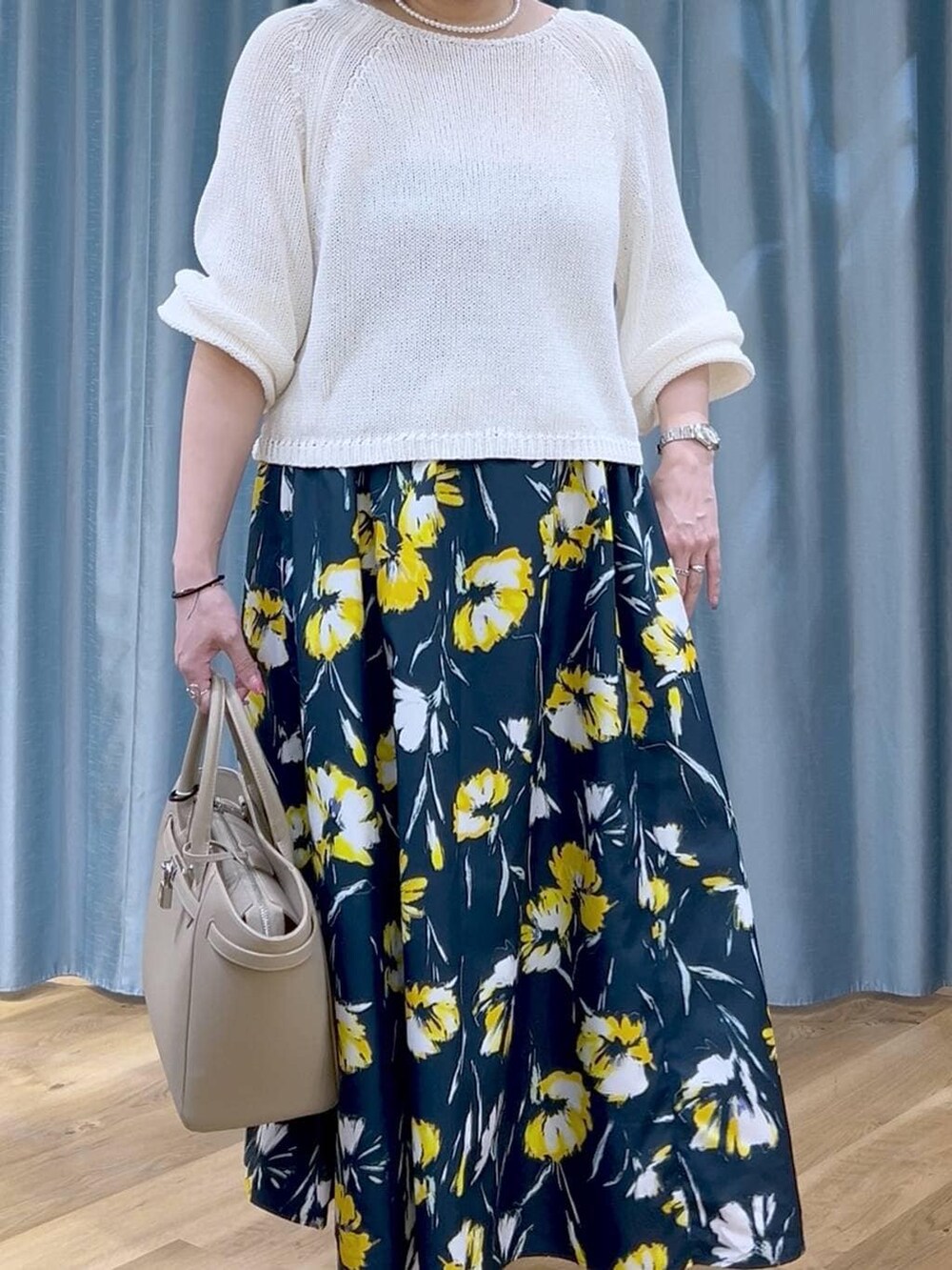 ホワイト系のニット/セーター、ブルー系のスカート、ベージュ系のハンドバッグを着用したレディースの春コーディネートの5枚目の写真