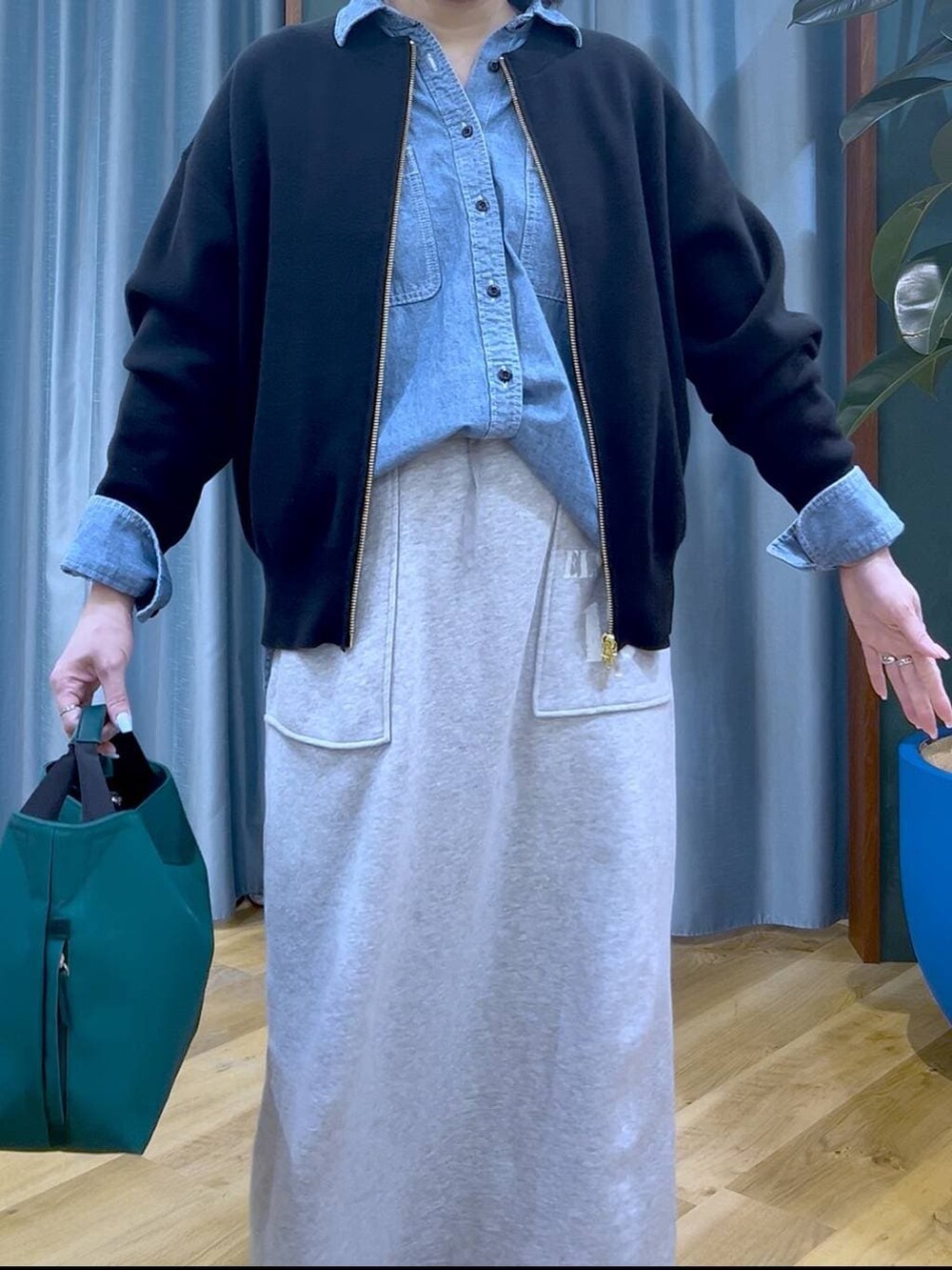 グリーン系のトートバッグ、ブラック系のカーディガン/ボレロ、グレー系のスカートを着用したレディースの冬コーディネートの5枚目の写真