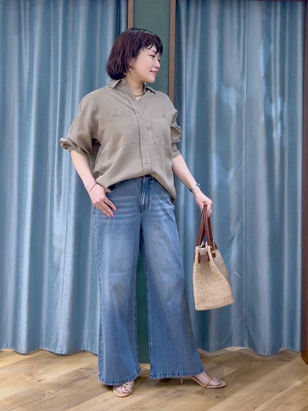 ブルー系のデニムパンツ、グリーン系のシャツ/ブラウス、ベージュ系のかごバッグを着用したレディースの春コーディネートの4枚目の写真