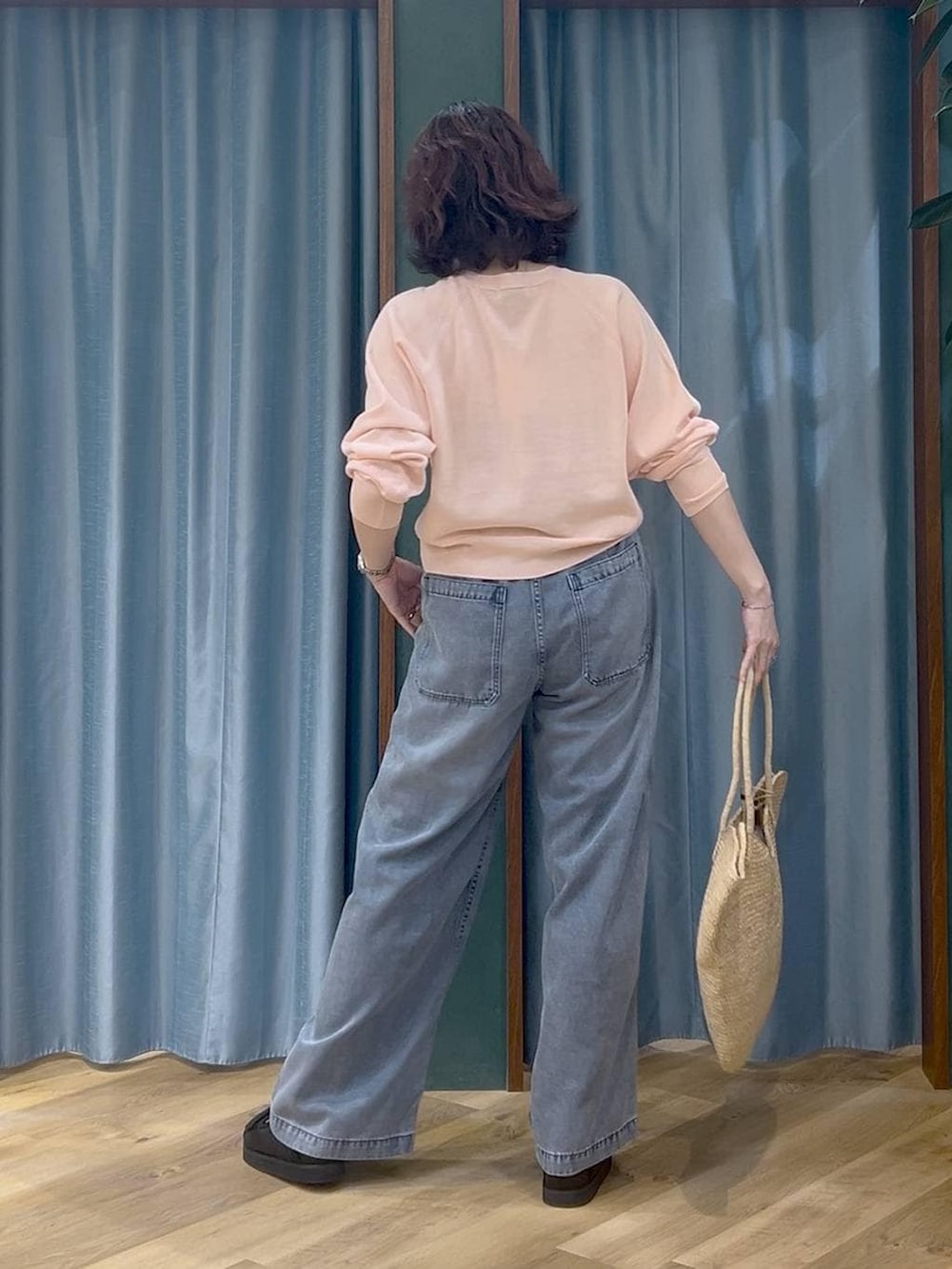 ブルー系のデニムパンツ、ピンク系のカーディガン/ボレロ、ベージュ系のかごバッグを着用したレディースの春コーディネートの4枚目の写真