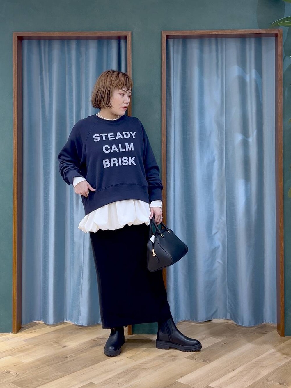 ブラック系のボストンバッグ、ブラック系のスカート、ホワイト系のTシャツ/カットソーを着用したレディースの秋コーディネートの2枚目の写真