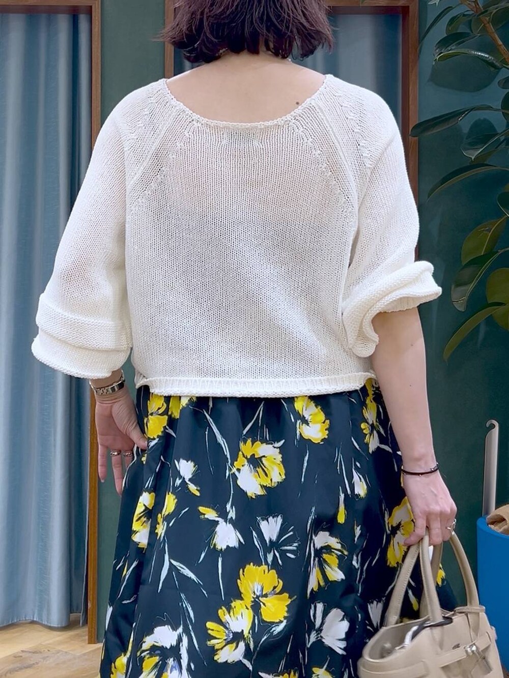 ホワイト系のニット/セーター、ブルー系のスカート、ベージュ系のハンドバッグを着用したレディースの春コーディネートの6枚目の写真