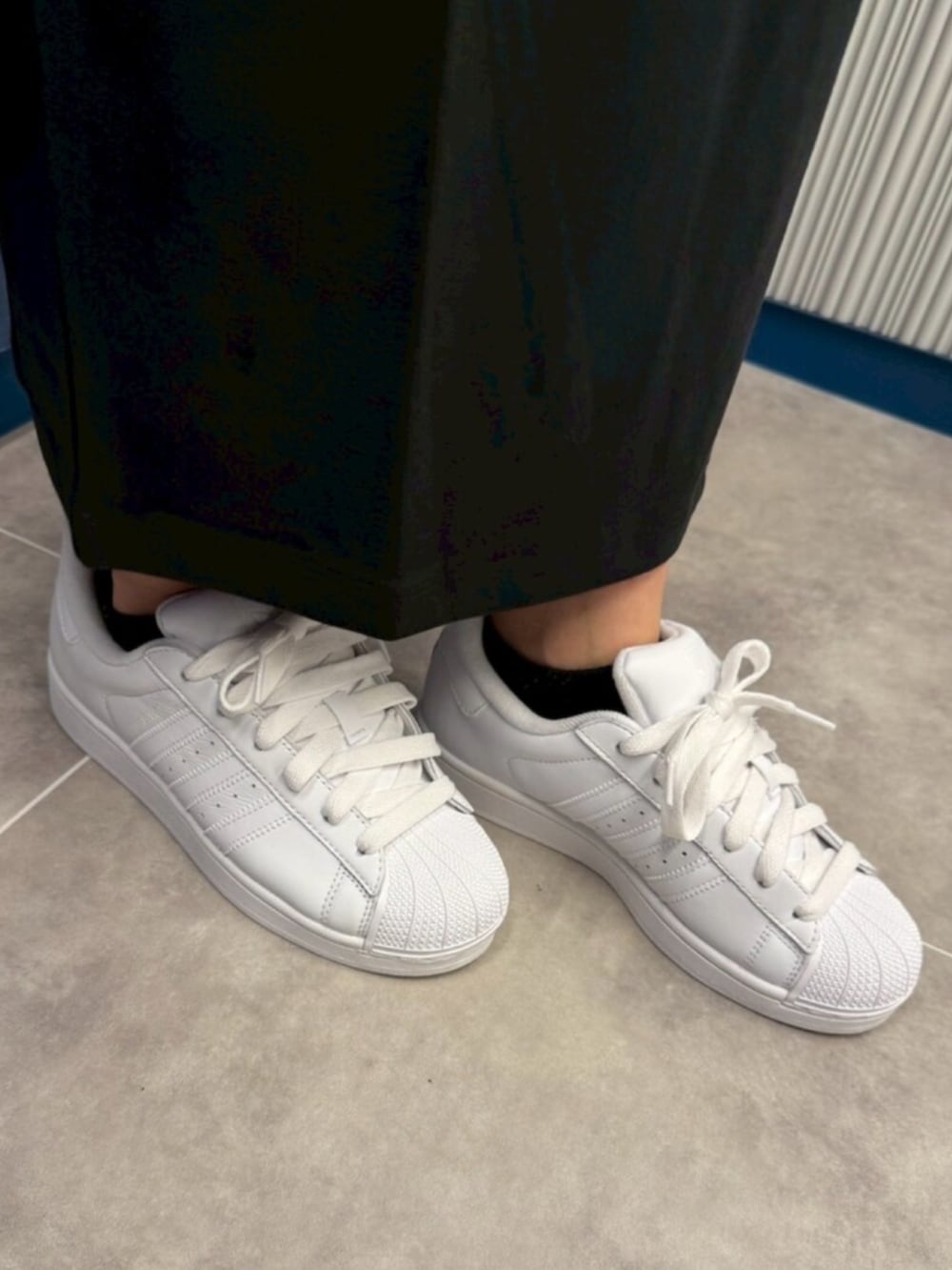 ホワイト系のスニーカー、ブラック系のワンピース、ブラック系のバッグを着用したレディースの夏コーディネートの4枚目の写真