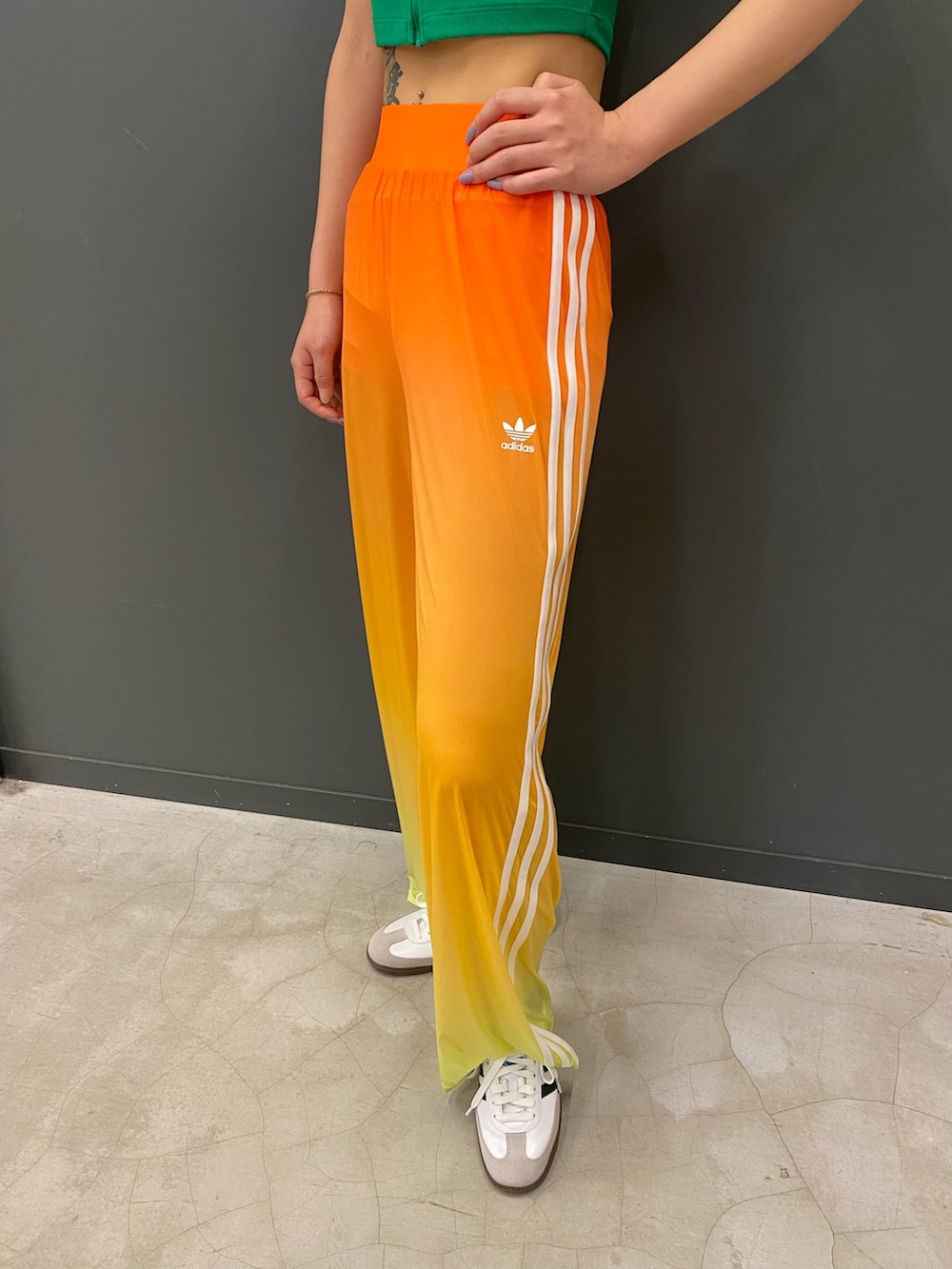 グリーン系のTシャツ/カットソー、オレンジ系のスウェットパンツ、ホワイト系のシューズを着用したレディースの春コーディネートの2枚目の写真