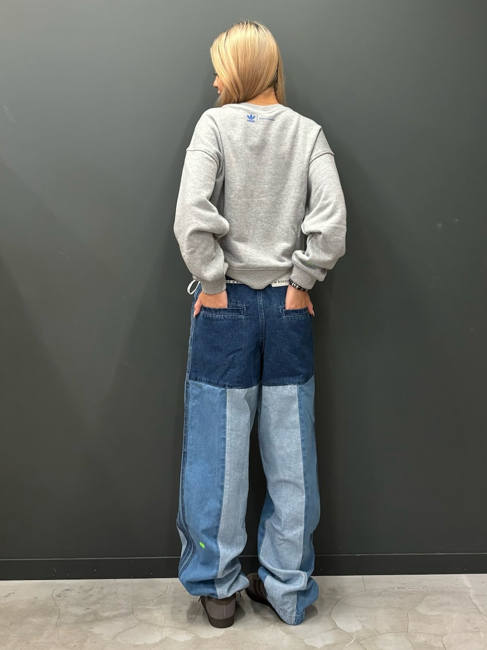 グレー系のスウェット、ブルー系のデニムパンツ、グレー系のシューズを着用したレディースの秋コーディネートの2枚目の写真