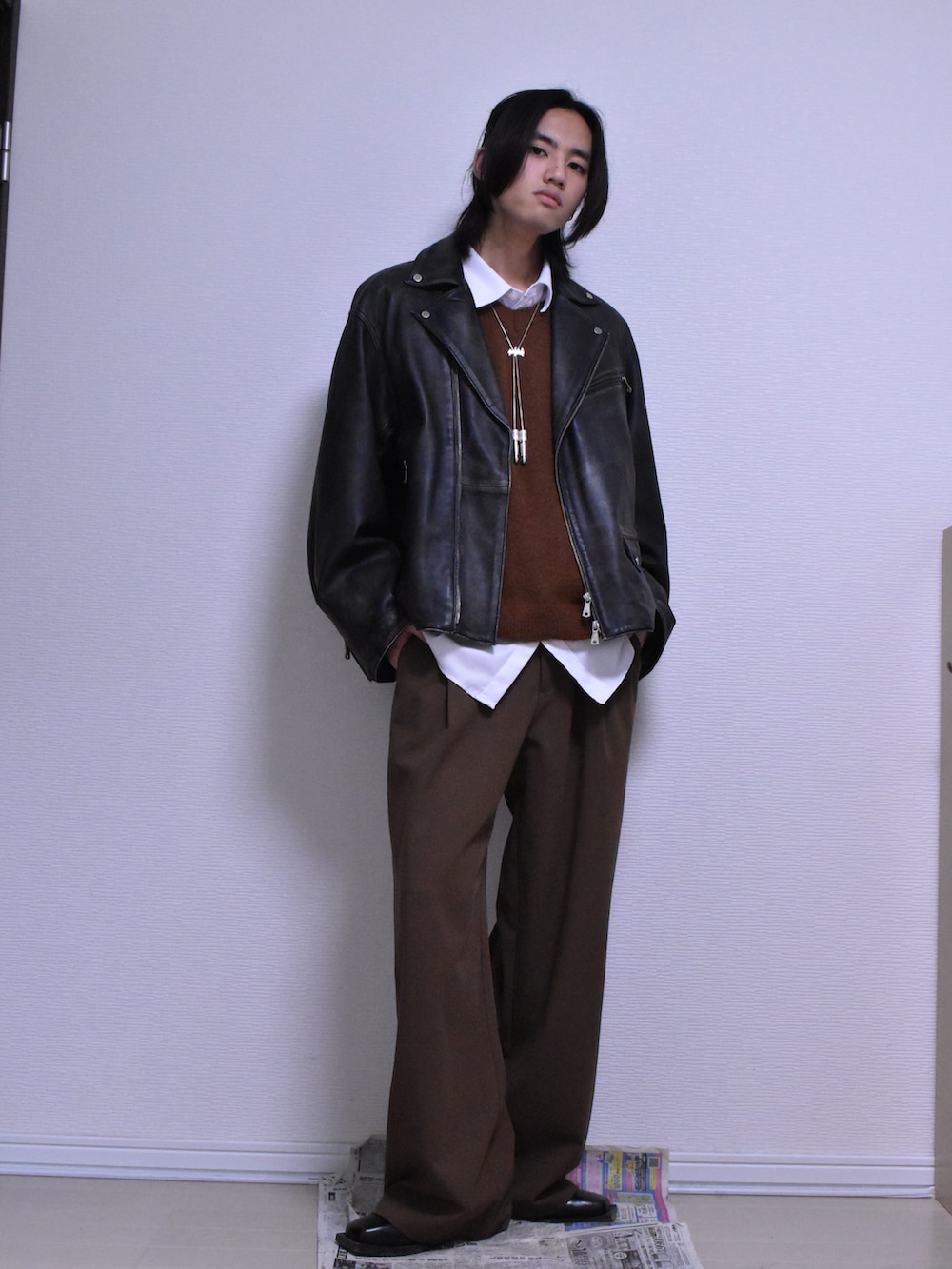 ブラウン系のスラックス、ブラック系のライダースジャケット、ブラウン系のニット/セーターを着用したメンズの冬コーディネートの4枚目の写真