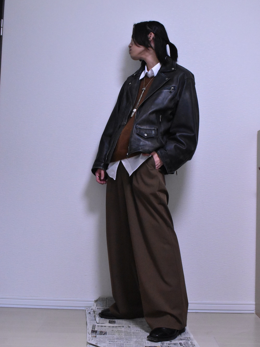 ブラウン系のスラックス、ブラック系のライダースジャケット、ブラウン系のニット/セーターを着用したメンズの冬コーディネートの2枚目の写真