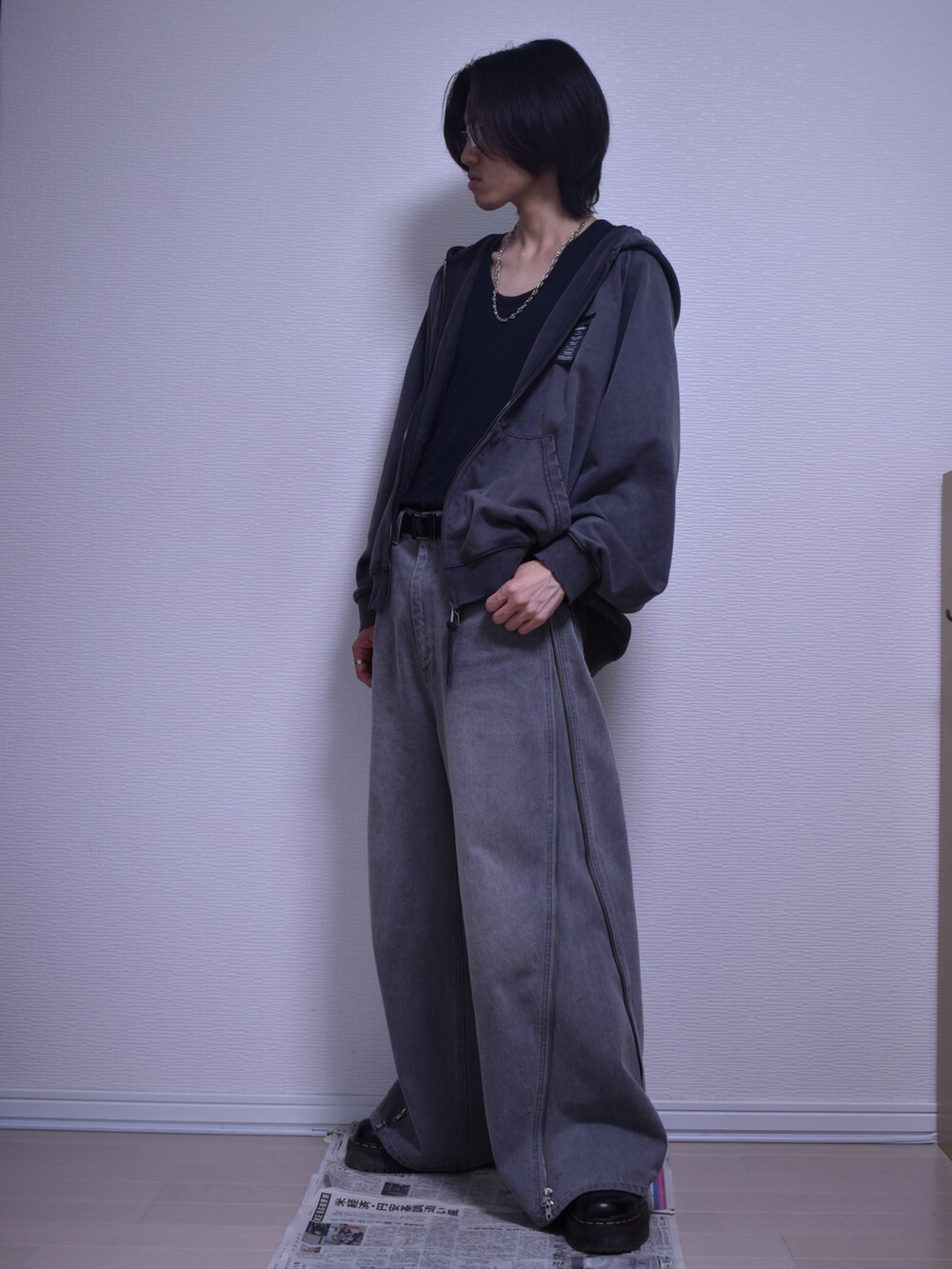 グレー系のパーカー、グレー系のデニムパンツ、ブラック系のブーツを着用したメンズの秋コーディネートの2枚目の写真
