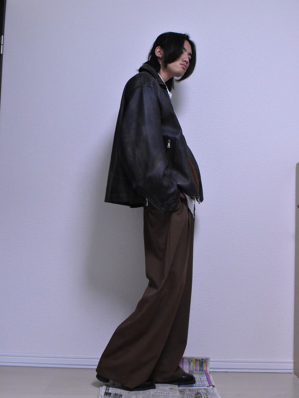 ブラウン系のスラックス、ブラック系のライダースジャケット、ブラウン系のニット/セーターを着用したメンズの冬コーディネートの5枚目の写真