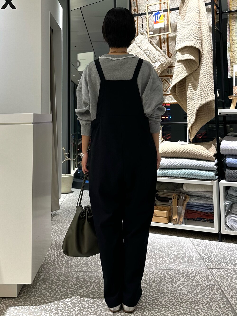 グレー系のスウェット、ブラック系のサロペット/オーバーオール、グリーン系のショルダーバッグを着用したレディースの秋コーディネートの3枚目の写真