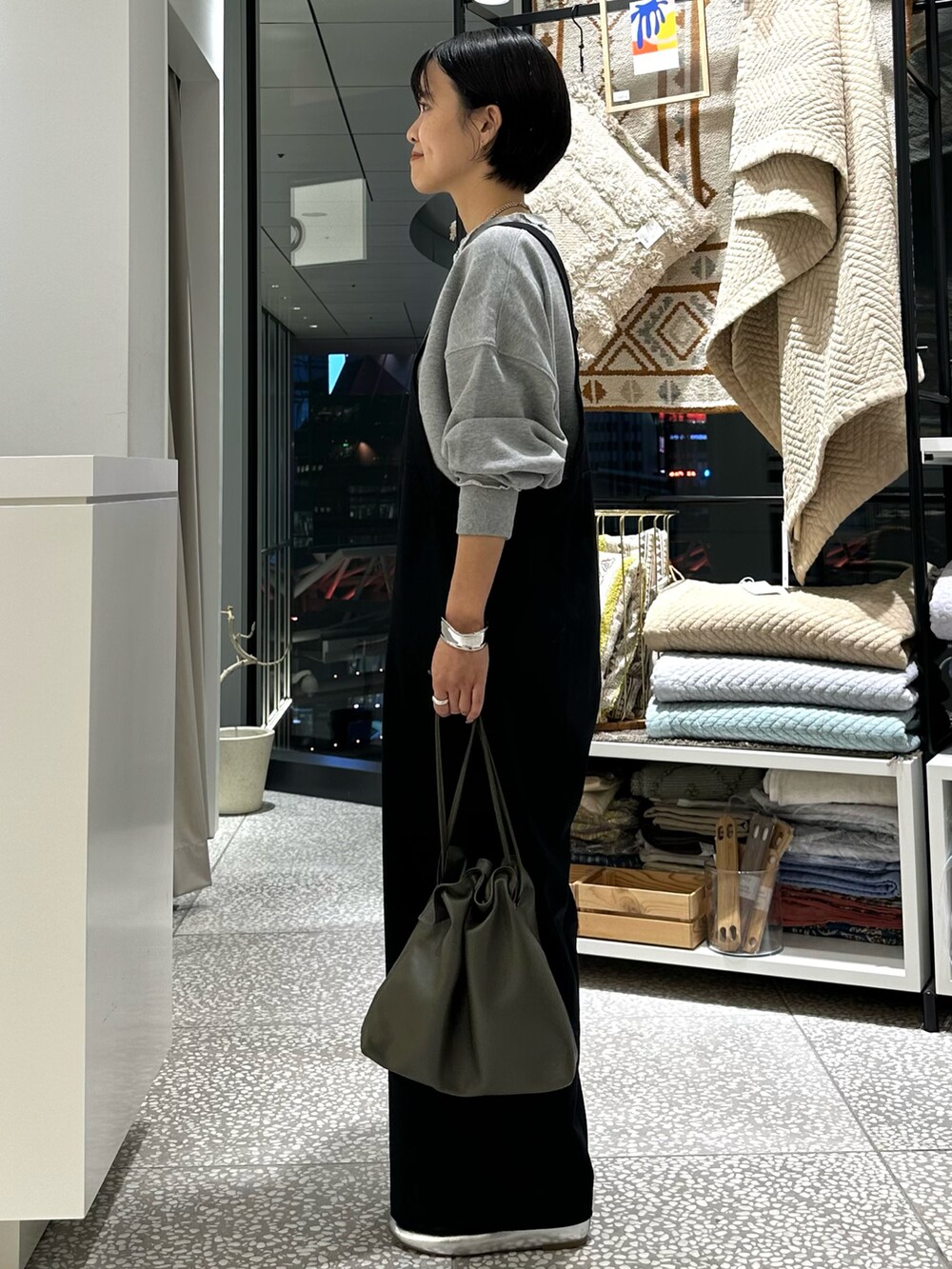 グレー系のスウェット、ブラック系のサロペット/オーバーオール、グリーン系のショルダーバッグを着用したレディースの秋コーディネートの2枚目の写真
