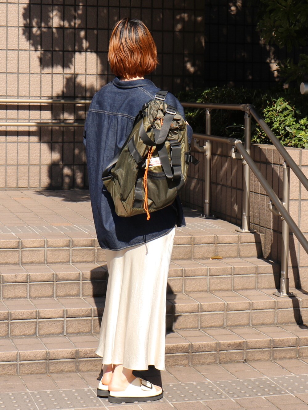 ブラック系のサンダル、ホワイト系のスカート、グリーン系のトートバッグを着用したレディースの春コーディネートの4枚目の写真