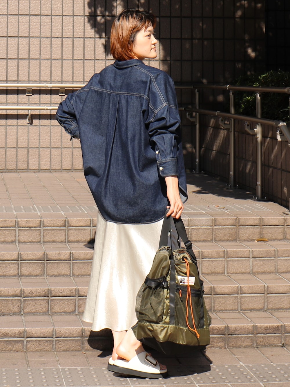 ブラック系のサンダル、ホワイト系のスカート、グリーン系のトートバッグを着用したレディースの春コーディネートの2枚目の写真