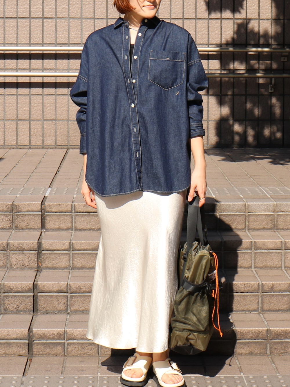 ブラック系のサンダル、ホワイト系のスカート、グリーン系のトートバッグを着用したレディースの春コーディネートの3枚目の写真