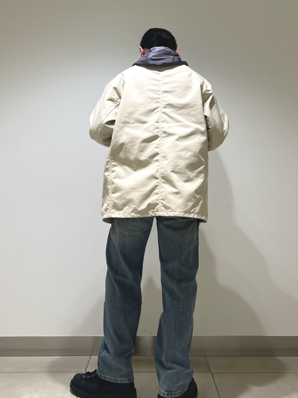 グレー系のパーカー、ホワイト系のカバーオール、ブルー系のデニムパンツを着用したメンズの冬コーディネートの3枚目の写真