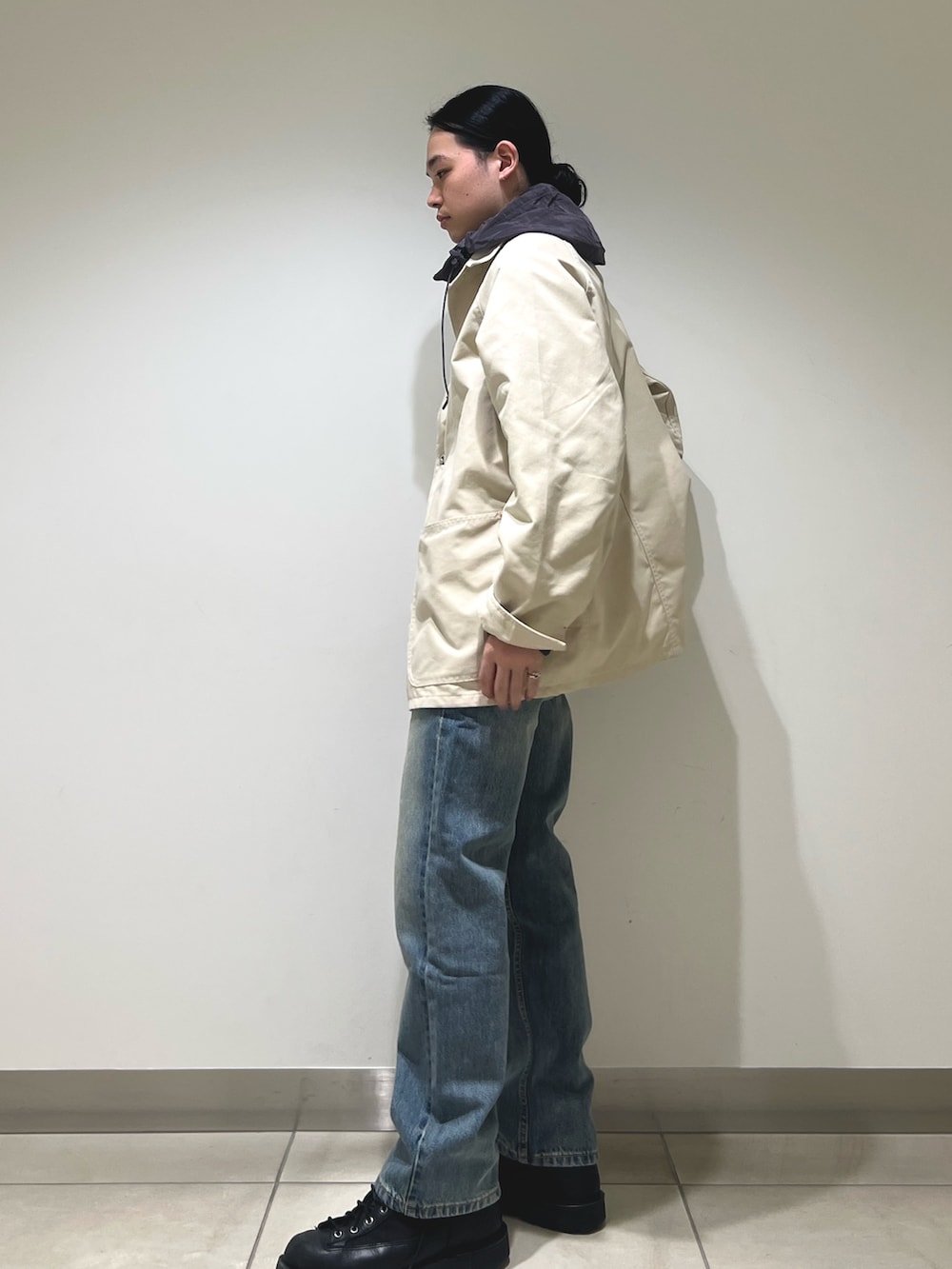 グレー系のパーカー、ホワイト系のカバーオール、ブルー系のデニムパンツを着用したメンズの冬コーディネートの2枚目の写真