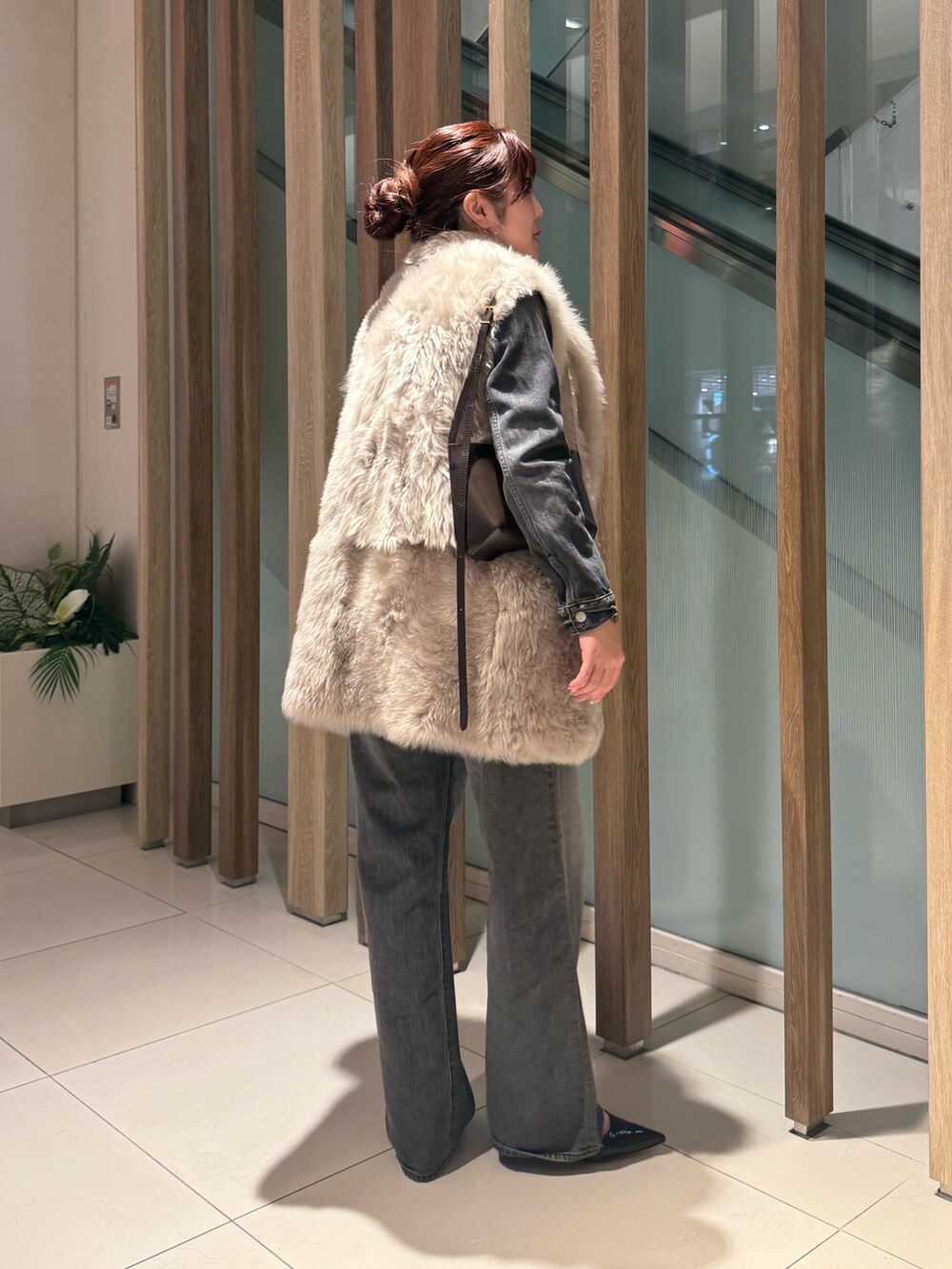 グレー系のデニムジャケット、グレー系のデニムパンツ、ベージュ系のベストを着用したレディースの冬コーディネートの2枚目の写真