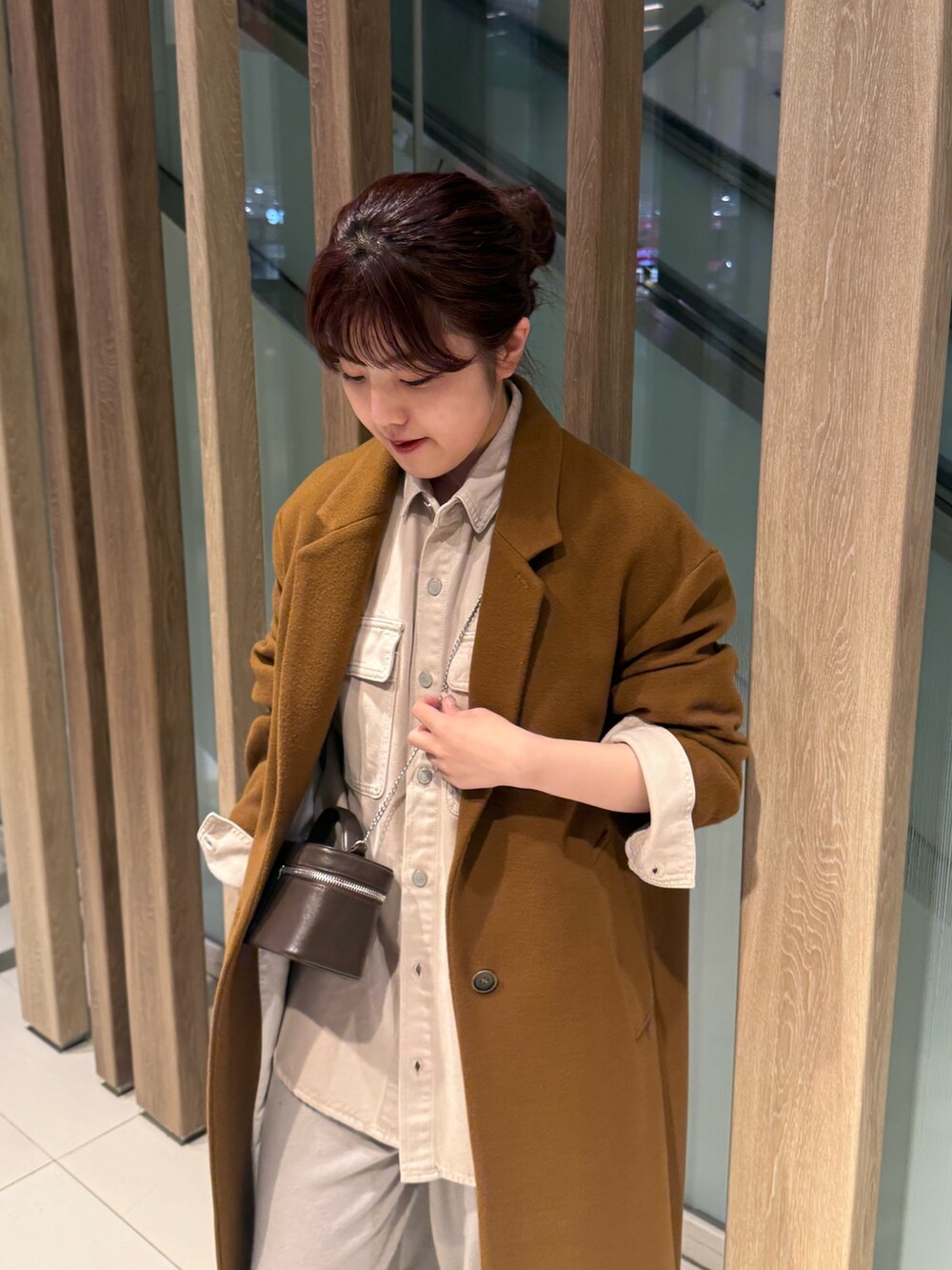 ベージュ系のシャツ/ブラウス、イエロー系のチェスターコート、ブラウン系のショルダーバッグを着用したレディースの冬コーディネートの3枚目の写真